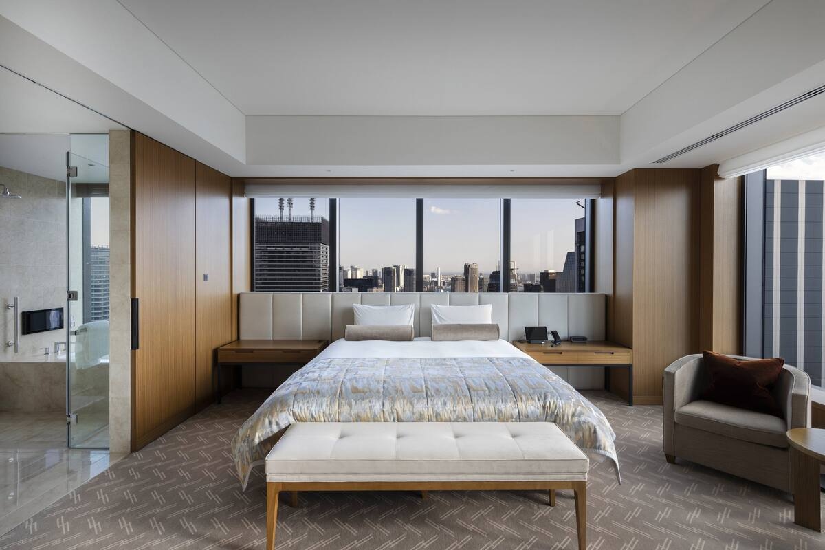 Ett modernt hotellrum med en stor säng, en sittgrupp och utsikt över staden.