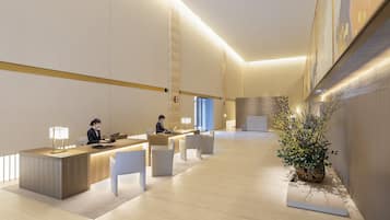 A modern reception area with a reception desk, two seating areas, and a potted plant.