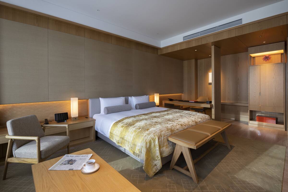 Ett modernt hotellrum med en stor säng, sängbord, ett skrivbord och en stol.
