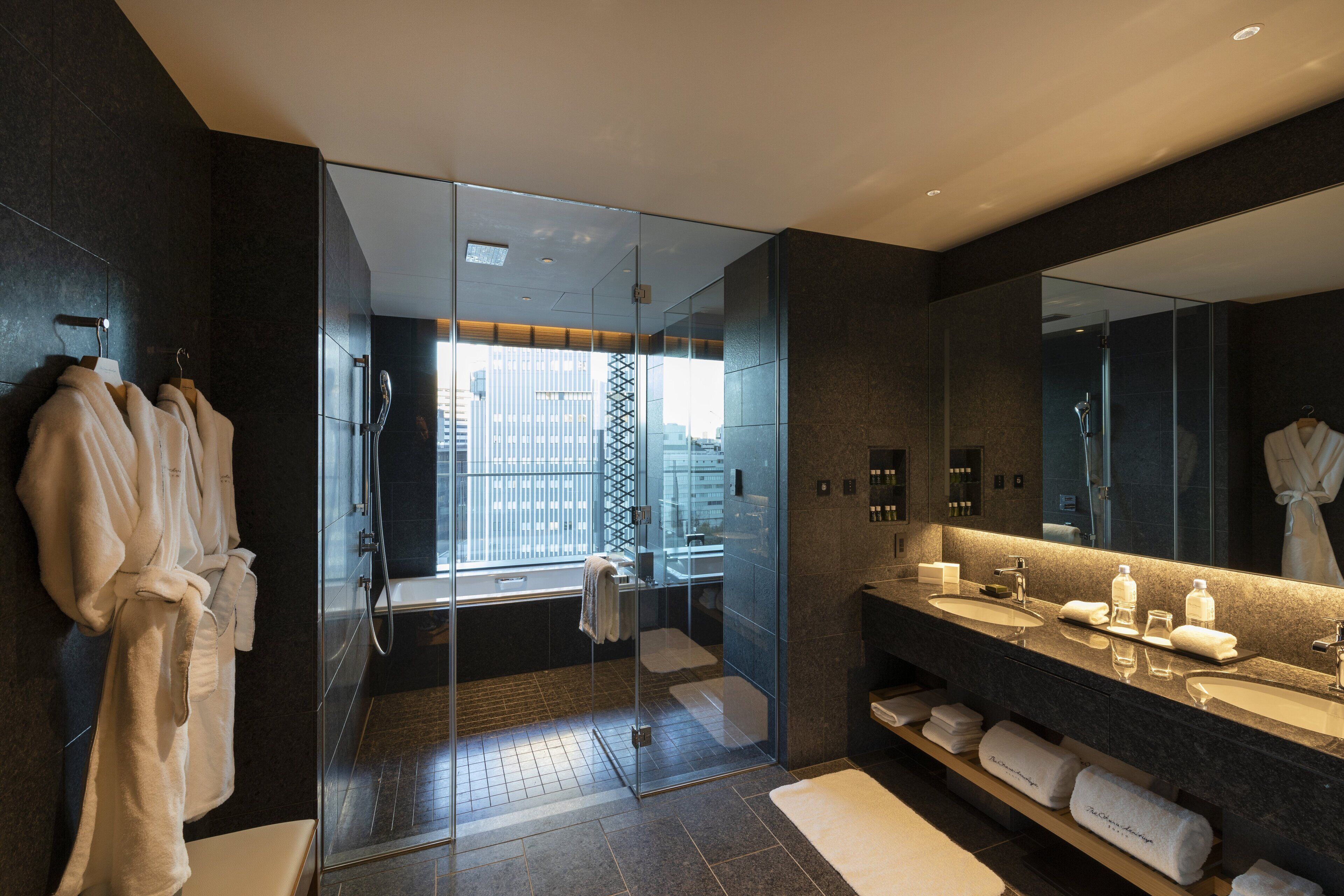 Un bagno moderno con doccia vetrata, uno specchio grande, e un mobile lavabo con diversi lavandini e articoli da toilette.