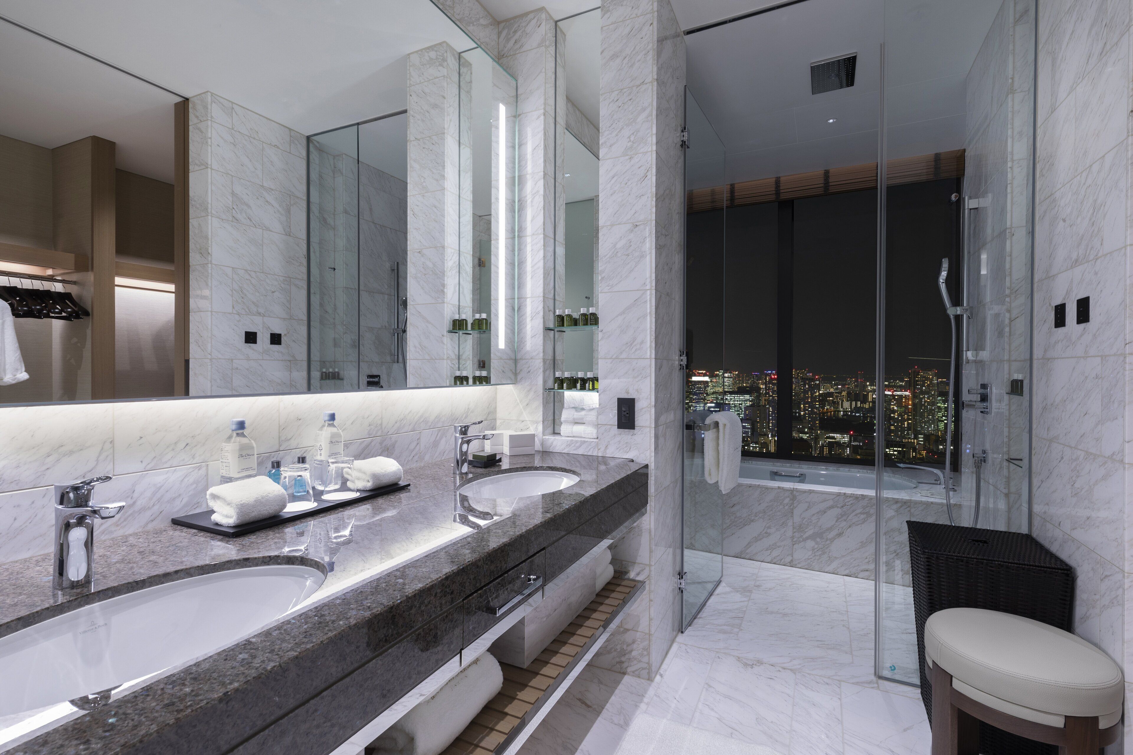 Un baño moderno con dos lavamanos, un espejo grande y una ducha con cerramiento de vidrio.