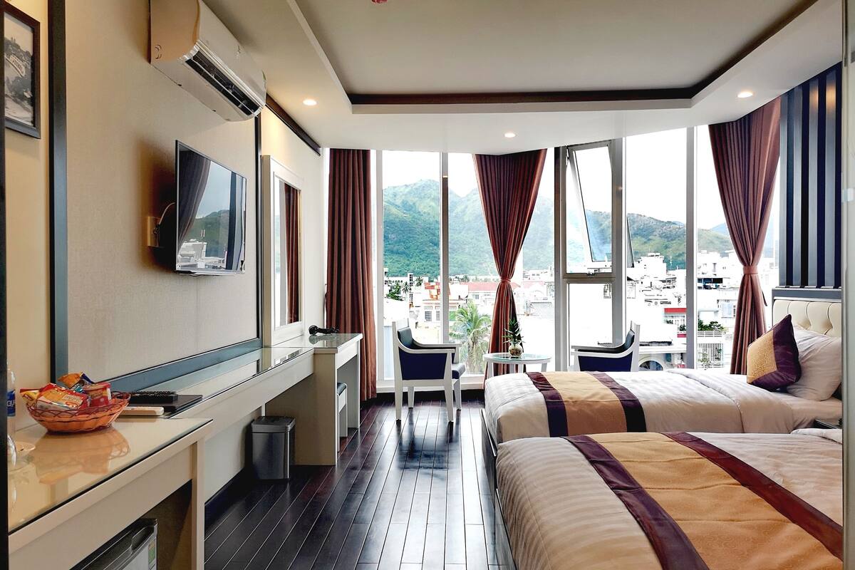 Une chambre d’hôtel avec un lit, un bureau, une télévision et une vue sur la ville.