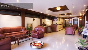 Un hall con sofás de cuero, un mostrador de recepción y una mesa de centro con flores.