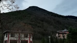 Ein Gebäude mit roter und weißer Fassade, einem Balkon und Blick auf einen Berg.