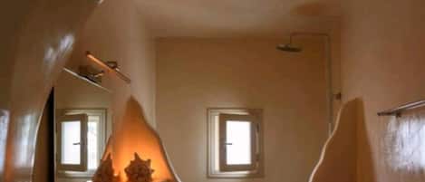 Un baño con un techo abovedado único, un lavamanos de madera, un espejo y una ventana pequeña.