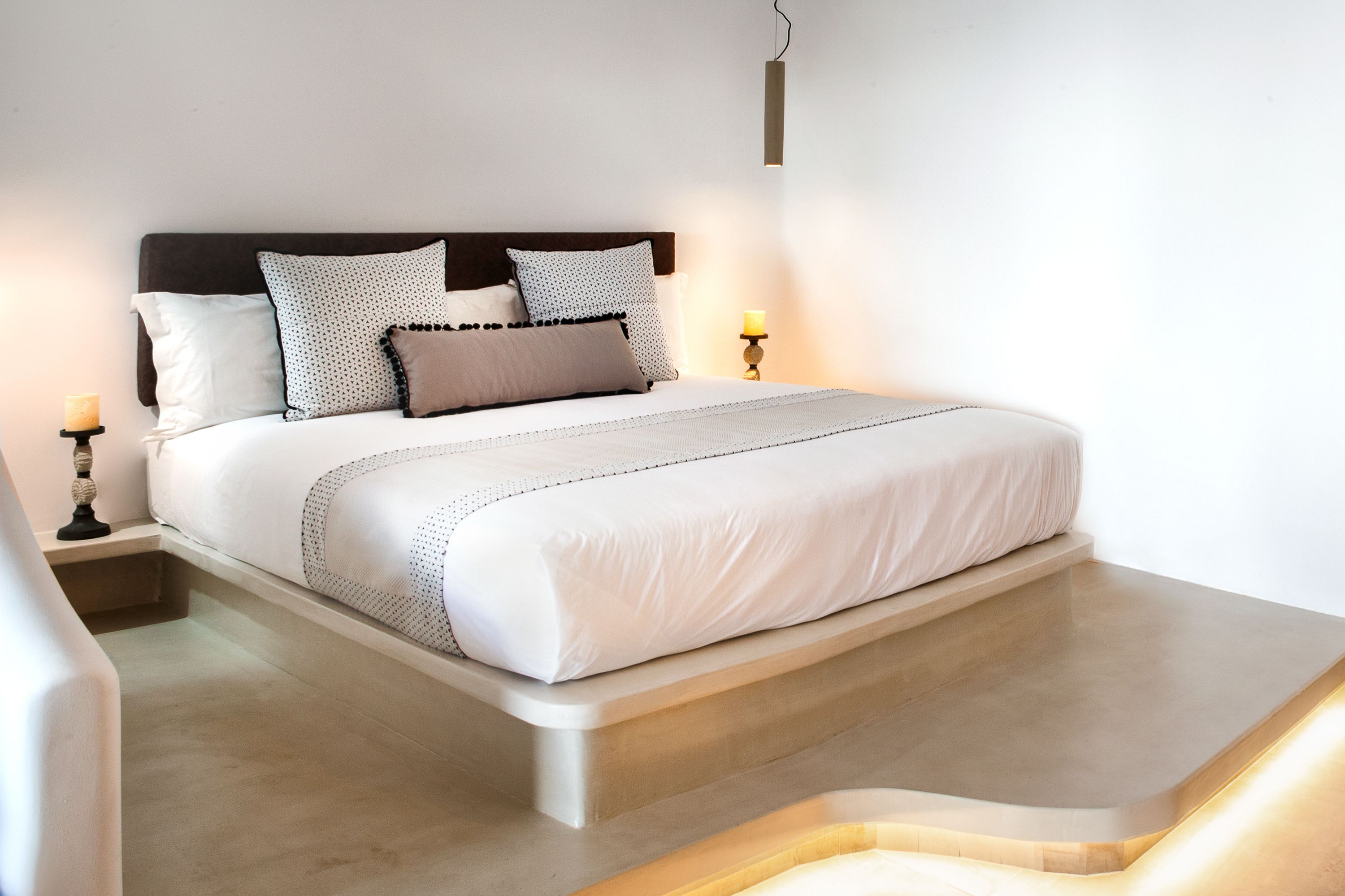 A modern bedroom with a large bed, a wooden headboard, and bedside lamps.