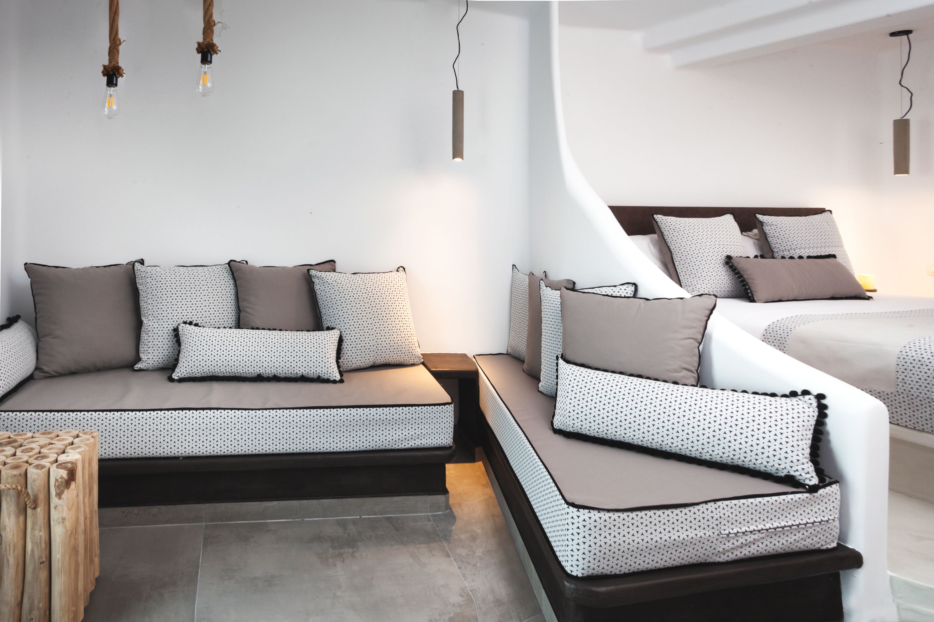 A modern bedroom with a sofa bed, a wooden side table, and a hanging light fixture.