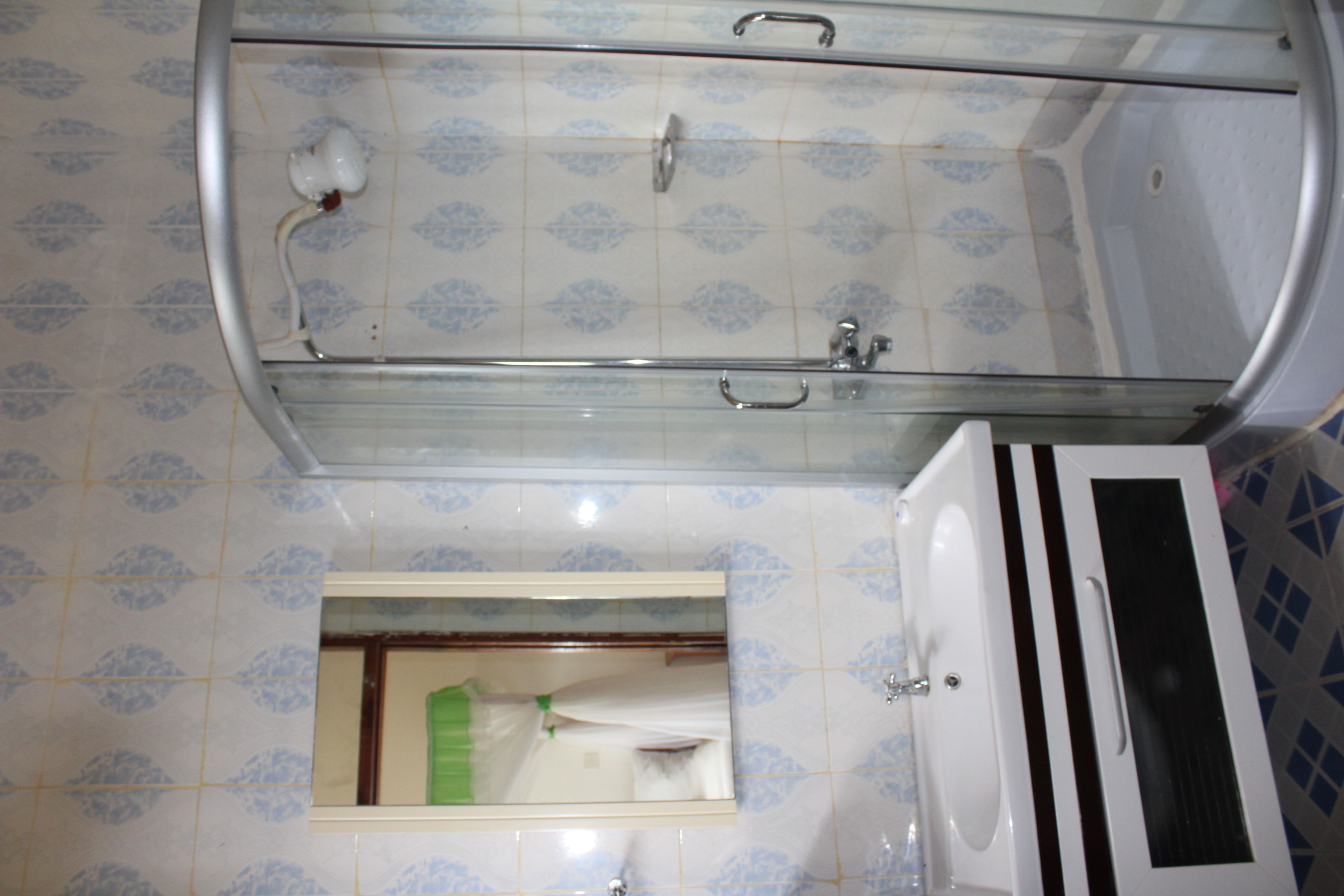 Ein Badezimmer mit Duschkabine aus Glas, Waschbecken und Spiegel.