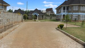 A residential street with houses, paved sidewalks, and small trees. - Salient Home Stay (Eldoret)