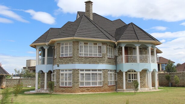 A large, multi-story house with a prominent turret and balcony, surrounded by a well-maintained lawn. - Salient Home Stay (Eldoret)