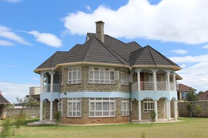 A large, multi-story house with a prominent turret and balcony, surrounded by a well-maintained lawn. - Salient Home Stay (Eldoret)