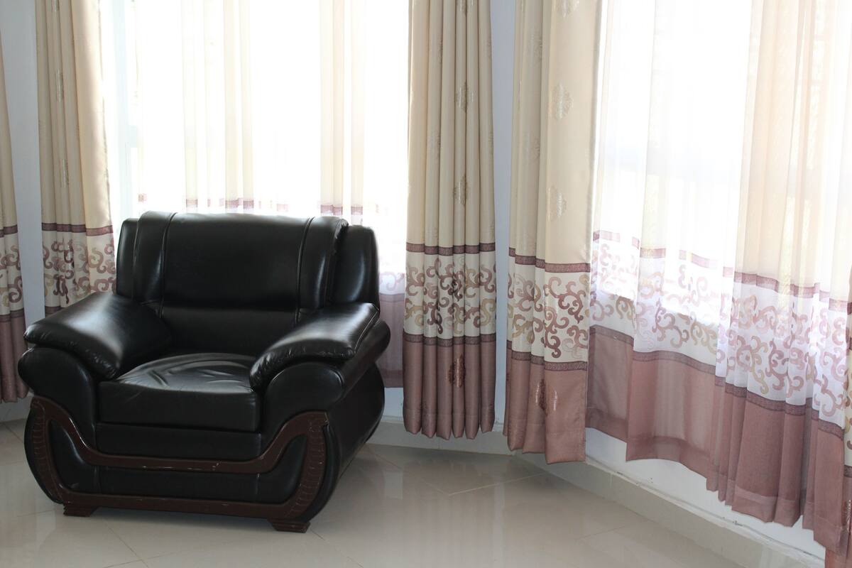 Un sillón de cuero negro en una habitación con cortinas estampadas.
