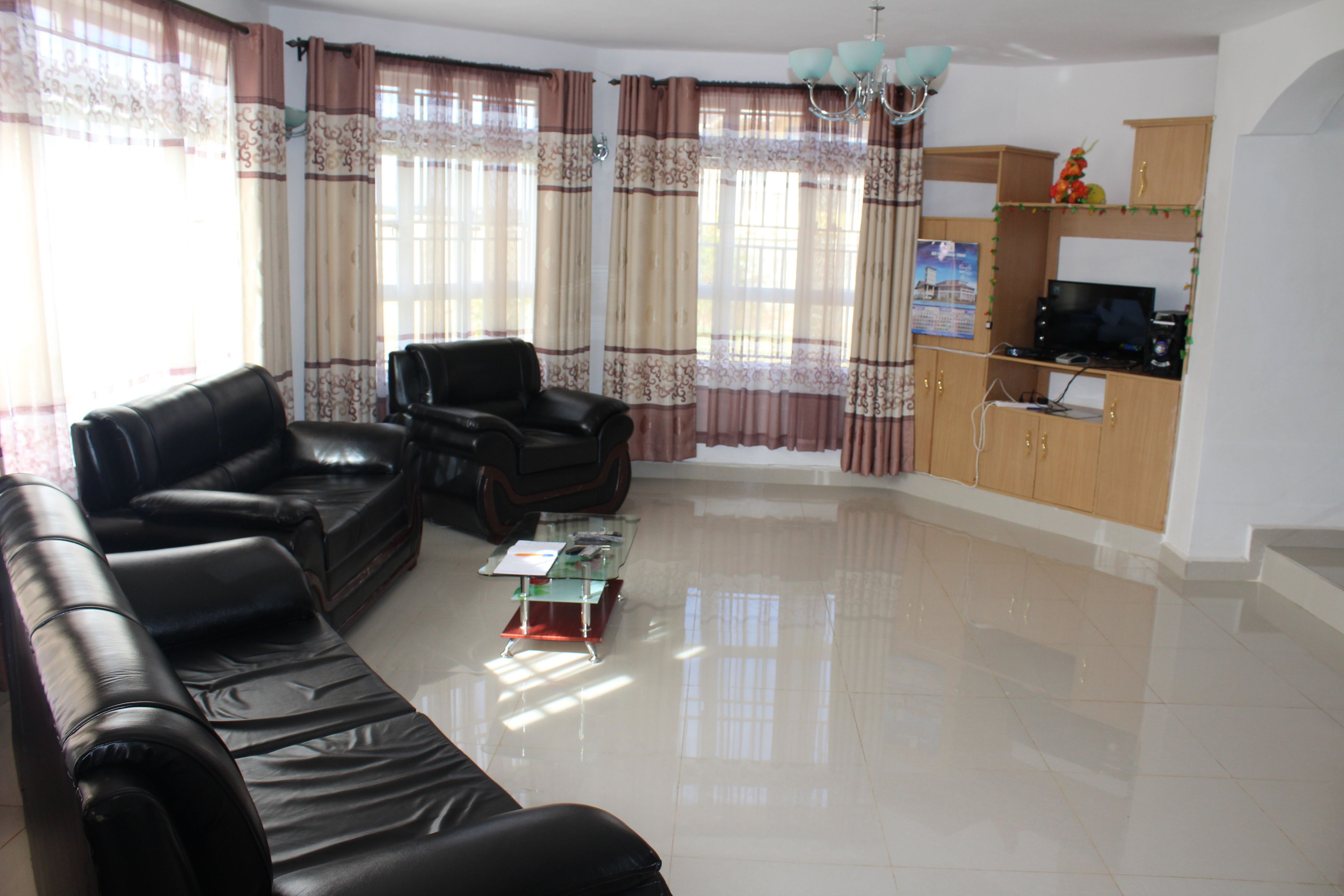 A living room with a leather sofa, a glass coffee table, and a television on a wooden cabinet.