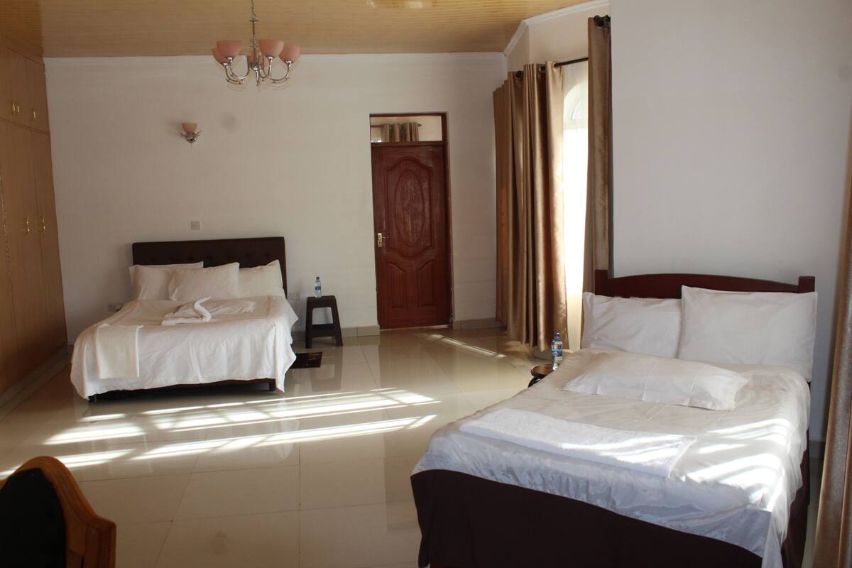 Habitación de hotel con dos camas, una puerta de madera y un candelabro.