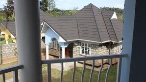 A residential house with a stone facade, a dark roof, and a visible front door. - Salient Home Stay (Eldoret)