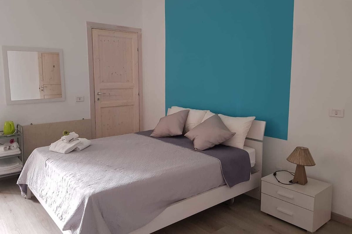 Une chambre à coucher avec un lit, une table de chevet, une lampe et une porte.