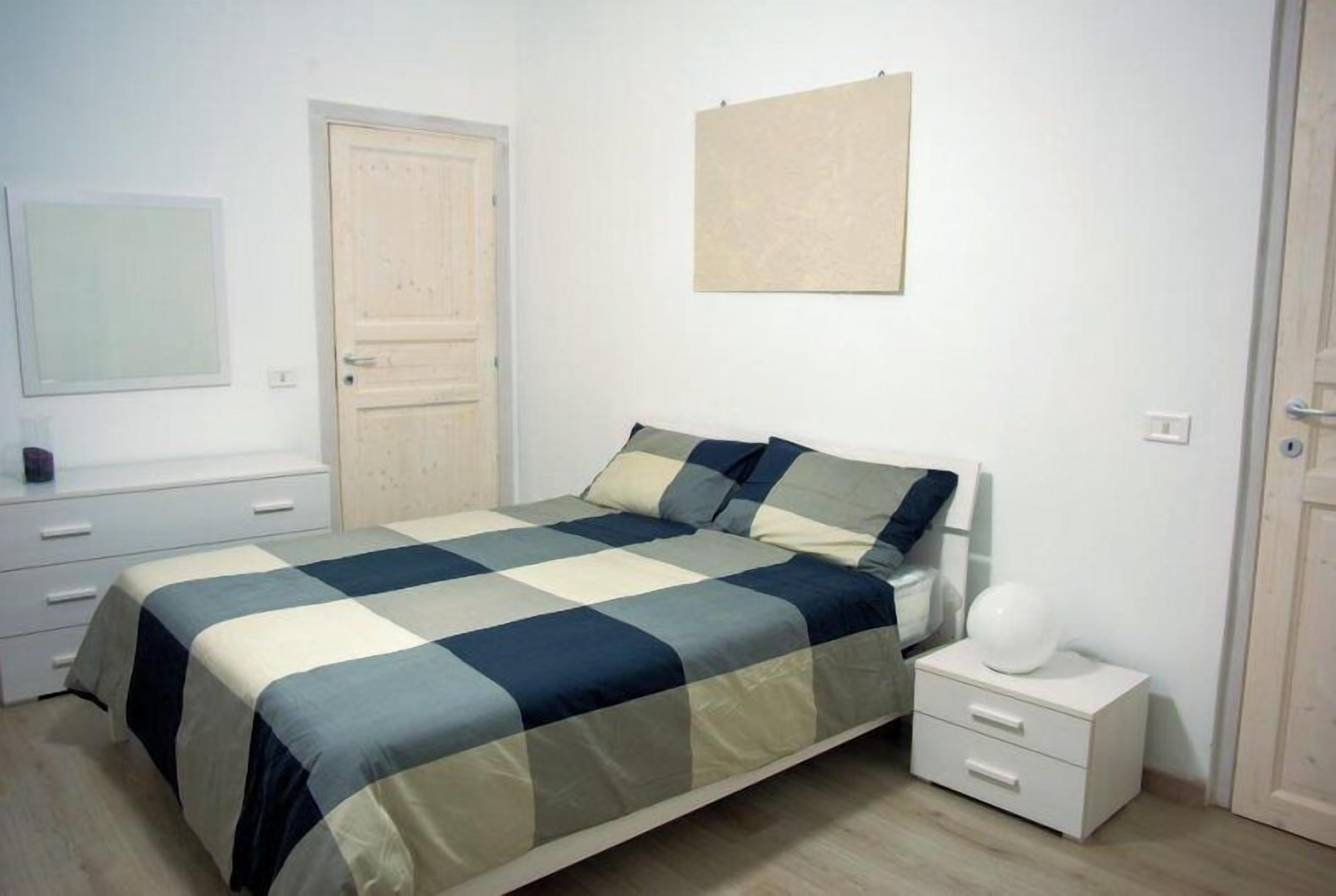 A bedroom with a bed, bedside tables, a wardrobe, and a wall-mounted artwork.