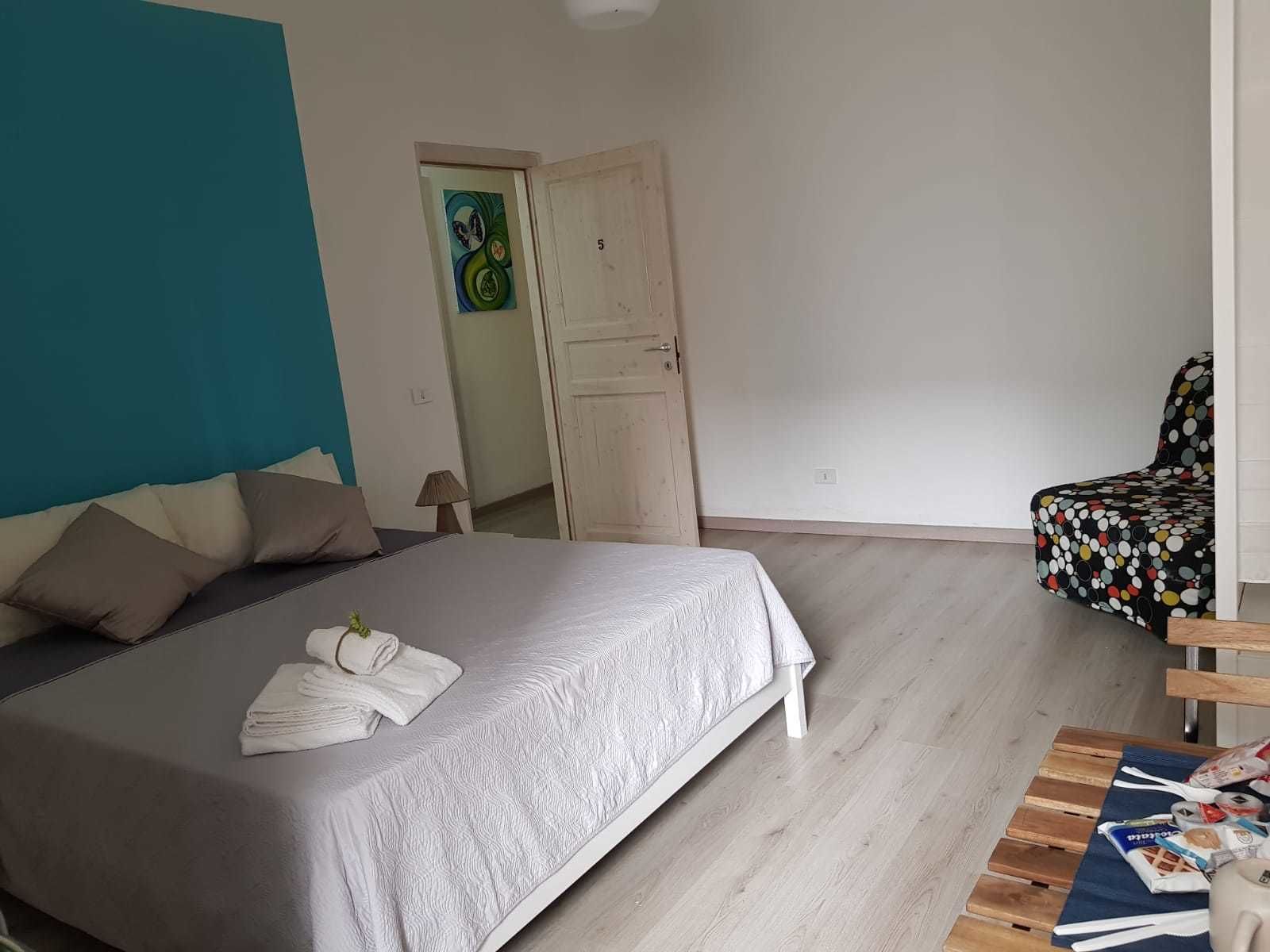 Ein Schlafzimmer mit einem Bett, Kissen, einem Sessel und einer Tür.
