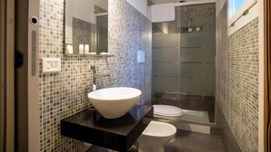 A modern bathroom with a large mirror, a white sink, and a glass-enclosed shower.