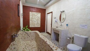 A bathroom with a large bathtub, a sink, a toilet, and a decorative wall. - Villa Go (Kerobokan Kaja)