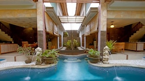 A pool area with a central water feature, surrounded by potted plants and stone statues. - Villa Go (Kerobokan Kaja)