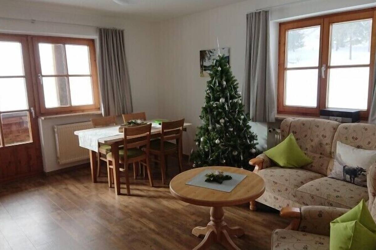 Ein gemütliches Wohnzimmer mit Esstisch, einer Couch und einem Weihnachtsbaum.