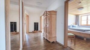 A spacious room with a wooden floor, a large wardrobe, a bed with a wooden headboard, and a window providing natural light. - Haflingerhof - Kematsried (Bad Hindelang)