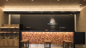 Un comptoir d’accueil au design moderne, agrémenté d’un mur recouvert de carreaux décoratifs et de deux tabourets.