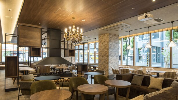Un café moderne avec des meubles en bois, un lustre et de grandes fenêtres donnant sur la rue.