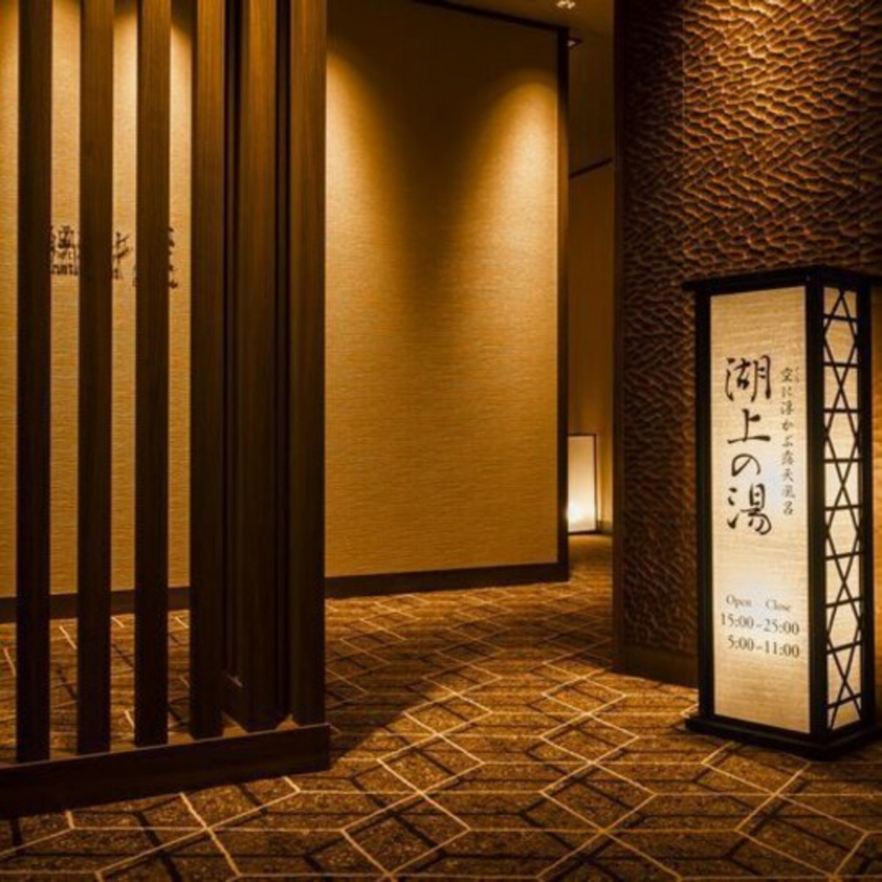 Un intérieur japonais traditionnel avec une porte coulissante en bois, un mur à texture et un panneau indiquant les heures d’ouverture.