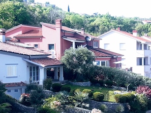 A residential area with houses featuring red and white exteriors, a stone wall, and well-maintained gardens. - Luxury Three-bedroom Apartment With Amazing Overlook at the sea (Opatija)
