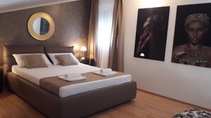 Ein Hotelzimmer mit einem großen Bett, einem runden Spiegel und zwei gerahmten Bildern an der Wand.