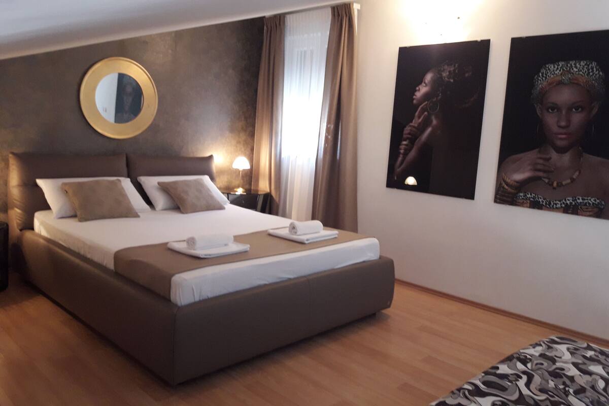 Ett hotellrum med en stor säng, en rund spegel och två inramade tavlor på väggen.