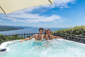 A couple in a hot tub with a scenic view of a lake and mountains. - Luxury Three-bedroom Apartment With Amazing Overlook at the sea (Opatija)