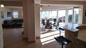 Ein modernes Wohnzimmer mit einer Eckcouch, einem Essbereich mit Tisch und Stühlen sowie einer Wand aus Stein.
