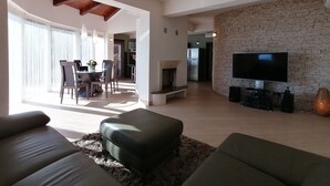 Ein modernes Wohnzimmer mit Kamin, Flachbildfernseher und Essbereich mit Tisch und Stühlen.