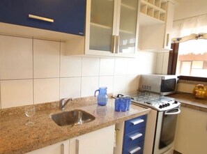 Une cuisine équipée d’un plan de travail en granit, d’un évier, d’un four à micro-ondes et d’une cuisinière.