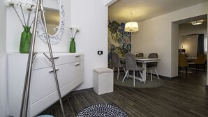A modern dining area with a table and chairs, a decorative mirror, and a vase with flowers.