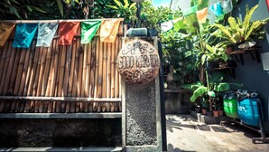 Une clôture en bambou, un panneau décoratif et des plantes en pot dans un espace aménagé en jardin.