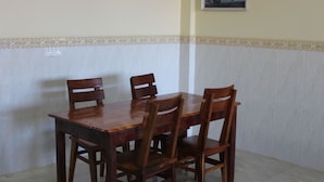 A dining table with four chairs in a room with a tiled floor and a decorative border along the lower wall. - Chambre en Ville (Sen Monorom)