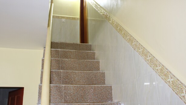 A staircase with a wooden handrail and a decorative border on the wall. - Chambre en Ville (Sen Monorom)