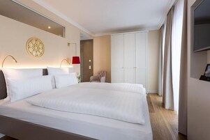 Ein Hotelzimmer mit einem großen Bett, einem Sessel, einem Kleiderschrank und einem Fernseher.