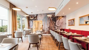 A restaurant with wooden floors, grey chairs, and red booths.