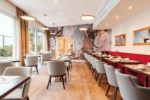 Ein Restaurant mit Holzdielen, grauen Stühlen und roten Sitzbänken.