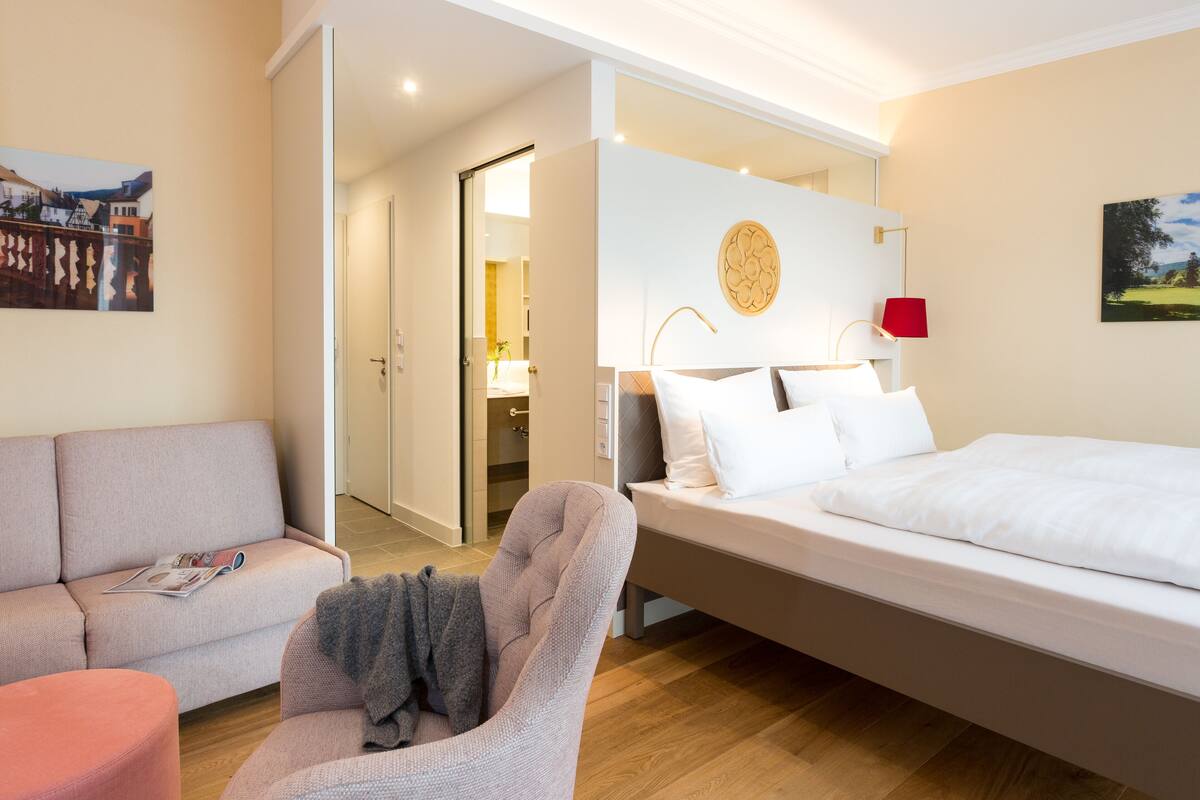 Una habitación de hotel moderna con una cama, un sofá, una silla y una mesita.