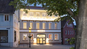 A hotel with a classic European facade, multiple windows, and a well-lit entrance.