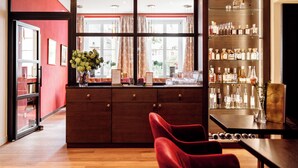 A bar area with a wooden counter, shelves of liquor bottles, and a red chair.