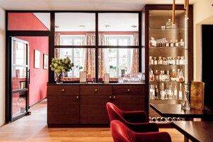Eine Bar mit einer Holztheke, Regalen voller Spirituosenflaschen und einem roten Sessel.