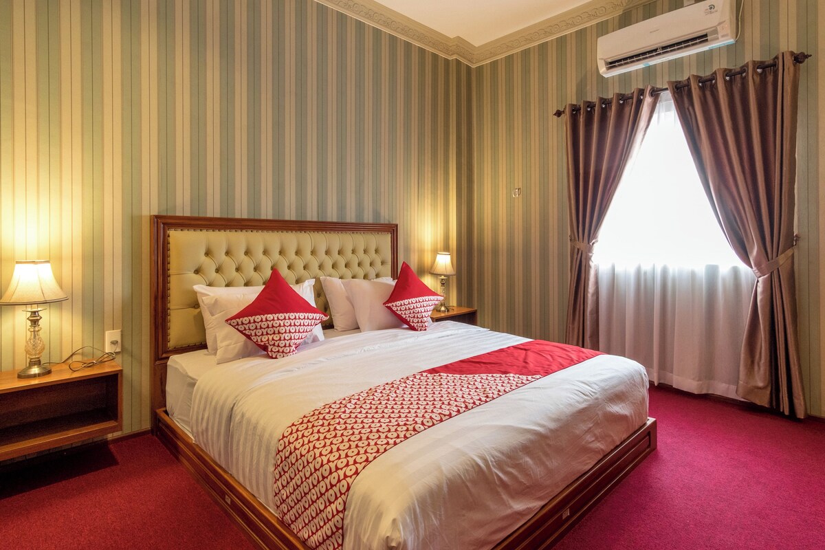Une chambre d’hôtel avec un grand lit, un papier peint à rayures et une fenêtre avec des rideaux.