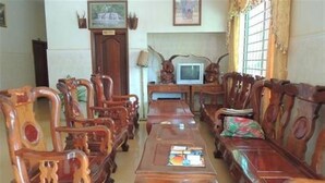 Een klassieke woonkamer met houten meubels, een televisie en een lijst met een foto.
